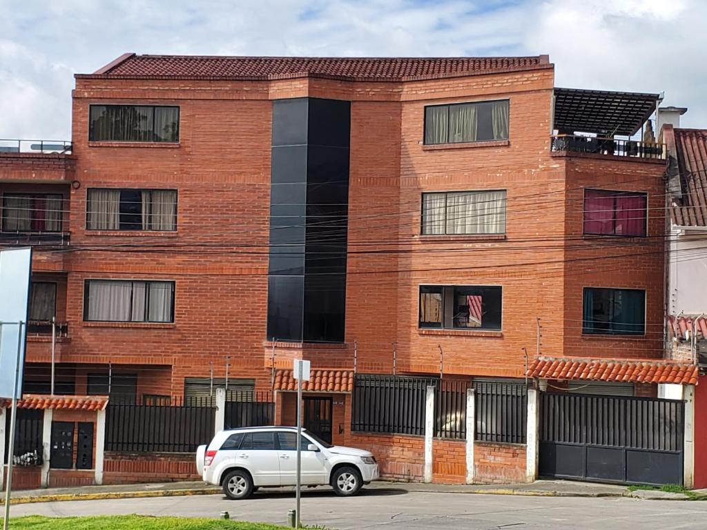 un coche aparcado frente a un edificio de ladrillo en Departamento en Cuenca, 3 Habitaciones y parqueo gratis, en Cuenca