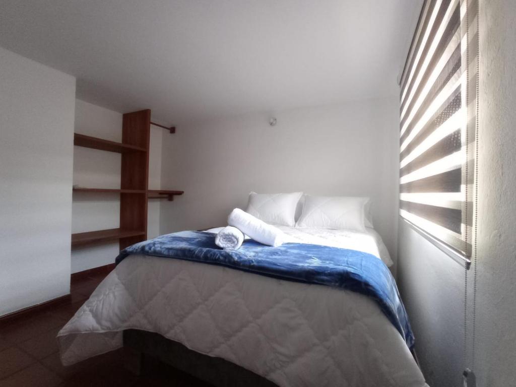 - une chambre avec un lit doté d'une couverture bleue et d'une fenêtre dans l'établissement Villa del Prado, à Villa de Leyva