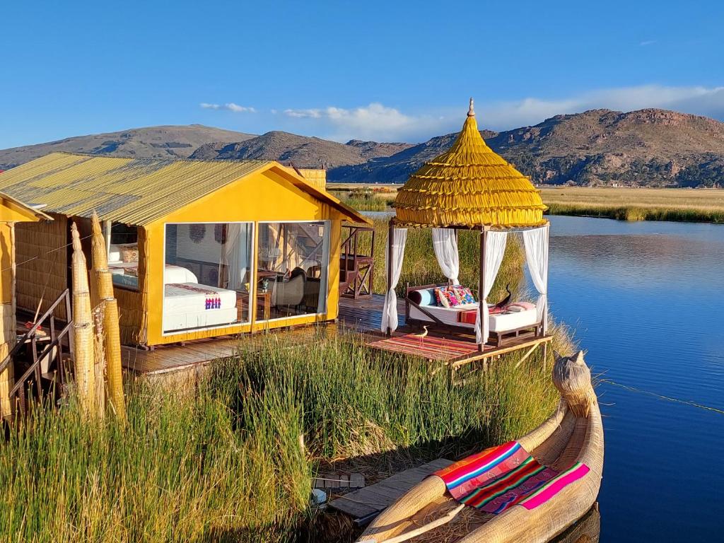 a house on the water with a boat in the water at Uros Lodge Perú in Puno