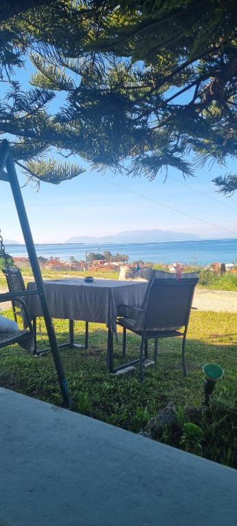 stół i krzesła siedzące na trawie blisko oceanu w obiekcie Voulitsa's Apartment w Kanalionie
