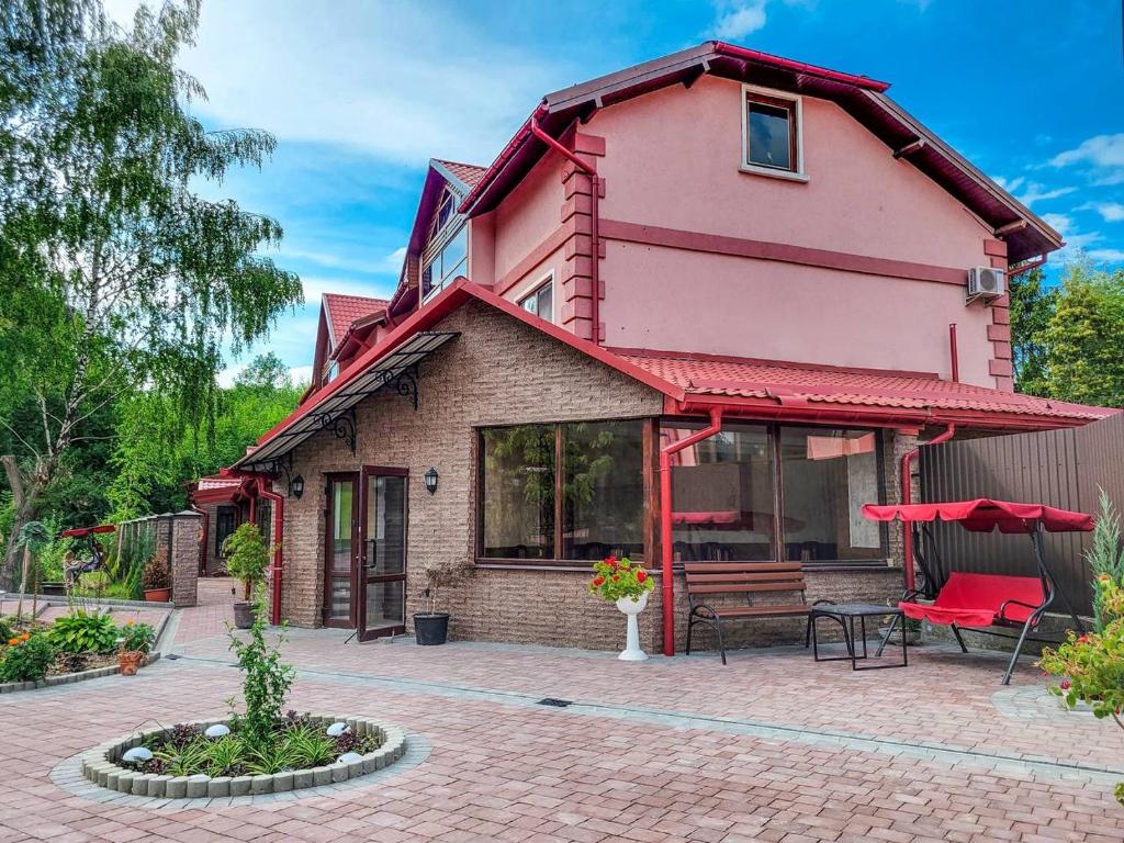 uma casa cor-de-rosa com um banco num pátio de tijolos em Glory em Truskavets