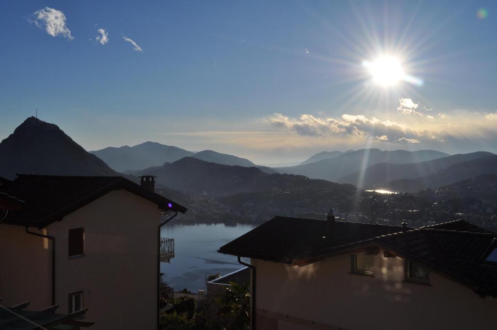 a view of a lake with the sun in the sky at Appartamenti Fortunella in Lugano