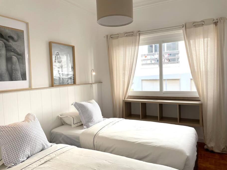 een slaapkamer met twee bedden en een raam bij Costa Beach in Costa da Caparica