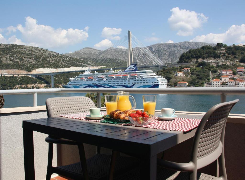 a table with a plate of food and a cruise ship at Apartments Marija Lapad in Dubrovnik