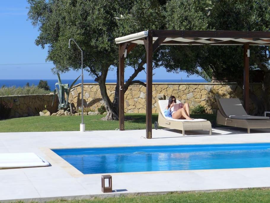 a woman sitting in a chair next to a swimming pool at Stone Villa Analisa, Pool, BBQ, Sunset Sea view in Kondomárion