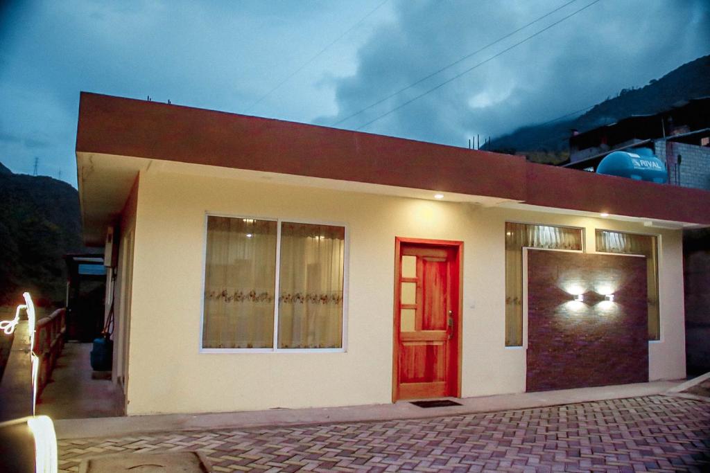 una pequeña casa con una puerta roja y una ventana en Casa de Campo - Baños de Agua Santa, en Juivi
