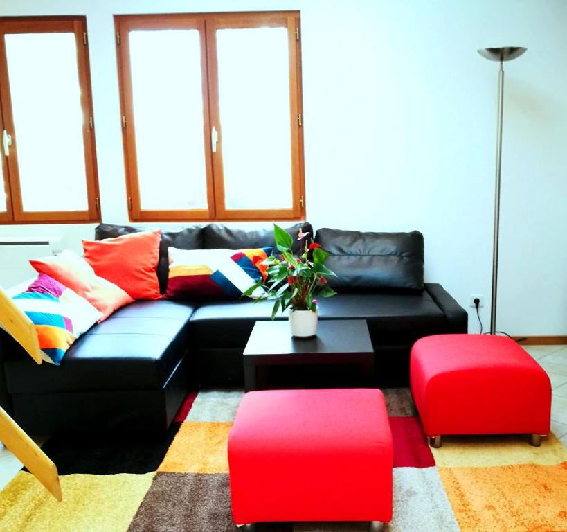 a living room with a black couch and red ottoman at Cozy Villa close to CERN, Geneva Airport, UN in Gex