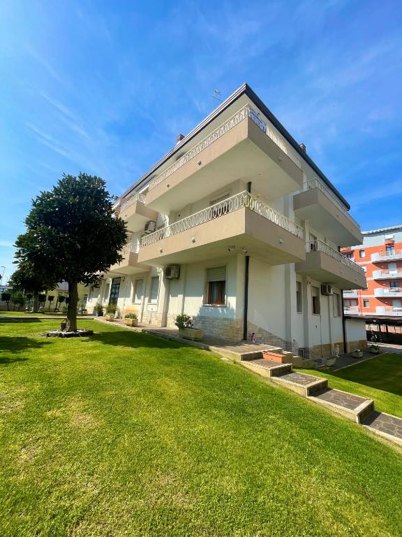 a large white building with a grass yard at Palazzina del sole in Sottomarina