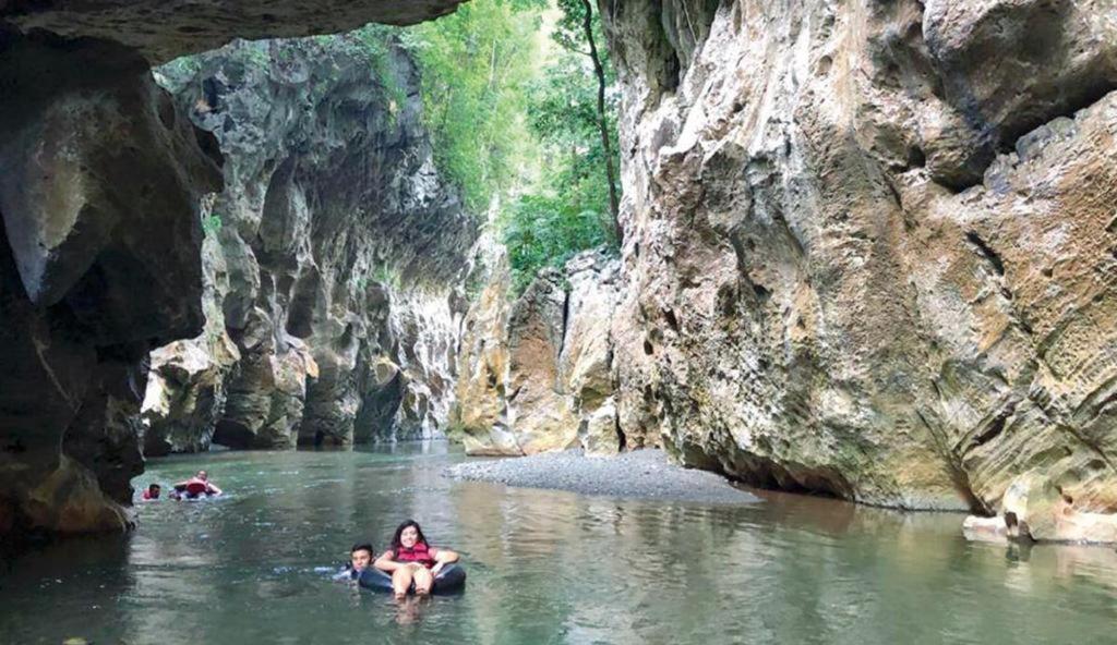 twee mensen zwemmen in een rivier in een grot bij Reserva Natural Cañón Seacacar in Izabal