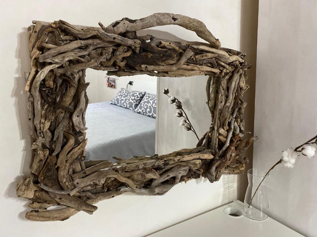 un miroir en bois flotté avec un cadre de branche sur un mur dans l'établissement B&B L'angolino, à Usigliano