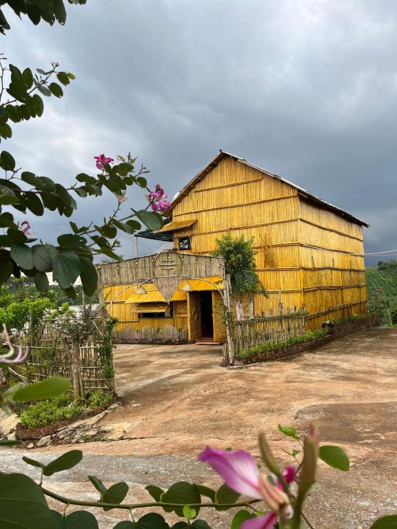 um velho celeiro de madeira com uma cerca e flores em Bamboo Villa em Gia Nghĩa