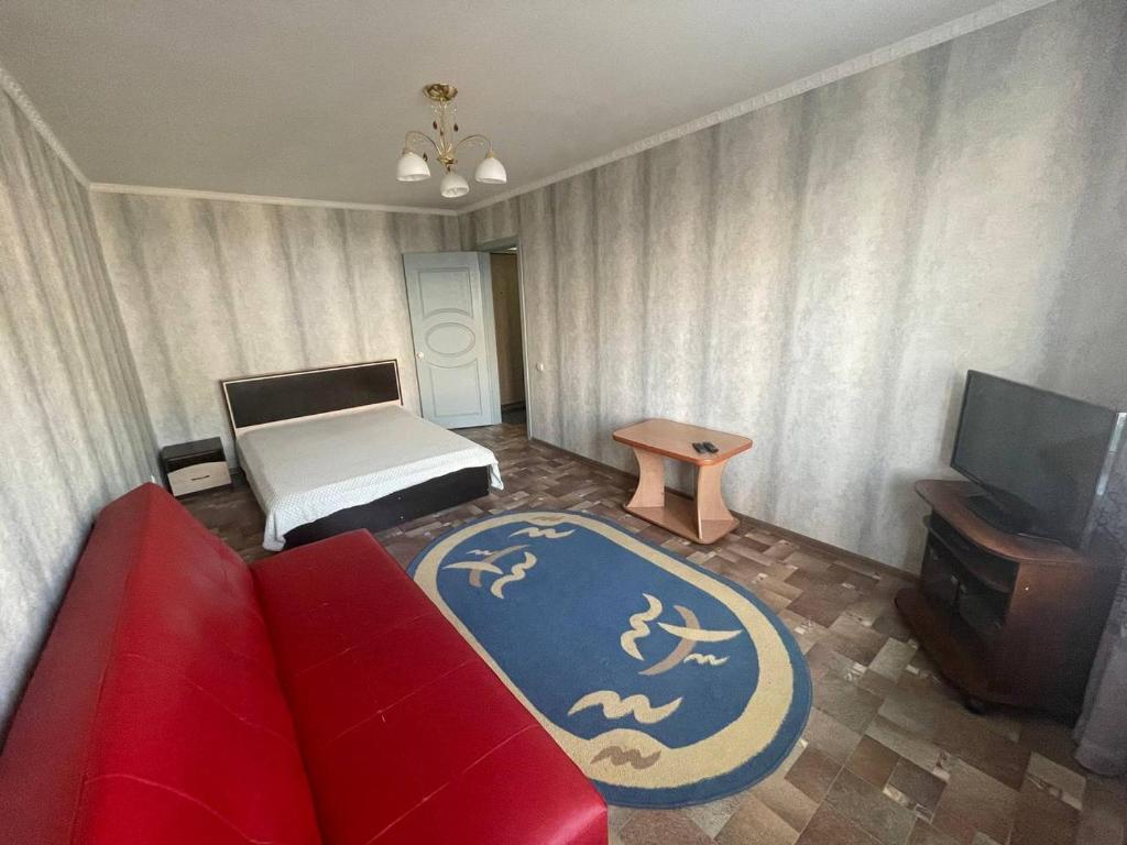 a living room with a red couch and a bed at 1-комнатная квартира в центре! in Petropavlovsk