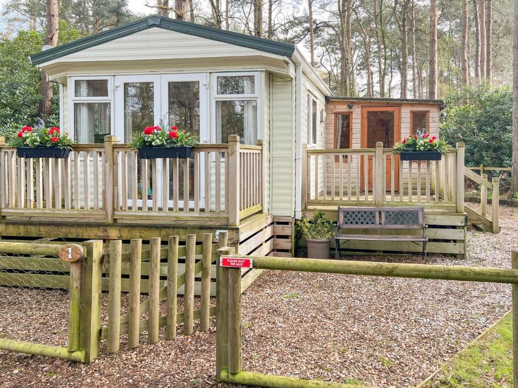 a tiny house with a fence and flowers on it at Robins Retreat in Weybourne