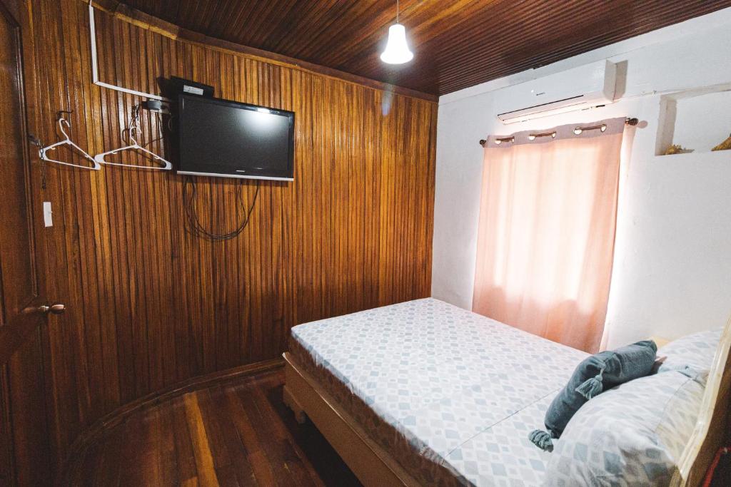 a bedroom with a bed and a tv on a wooden wall at Cat in The Cup B&B in Bocas Town