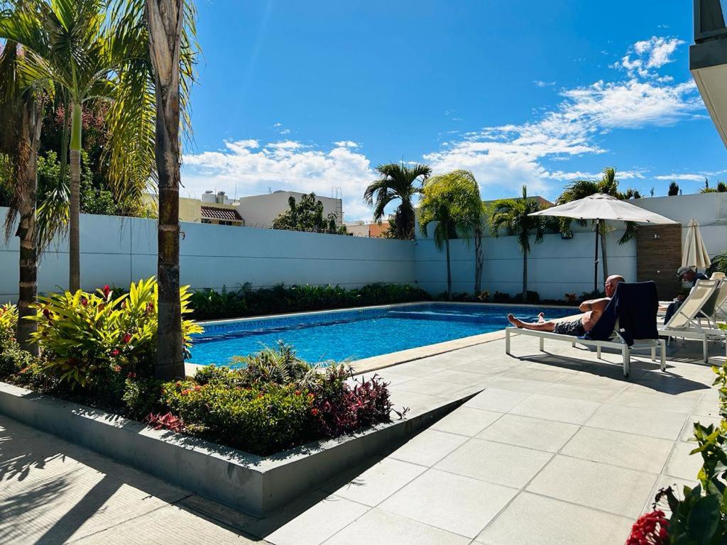 a man sitting in a chair next to a swimming pool at a 5 min de la playa alberca privada by G P S rentas in Mazatlán