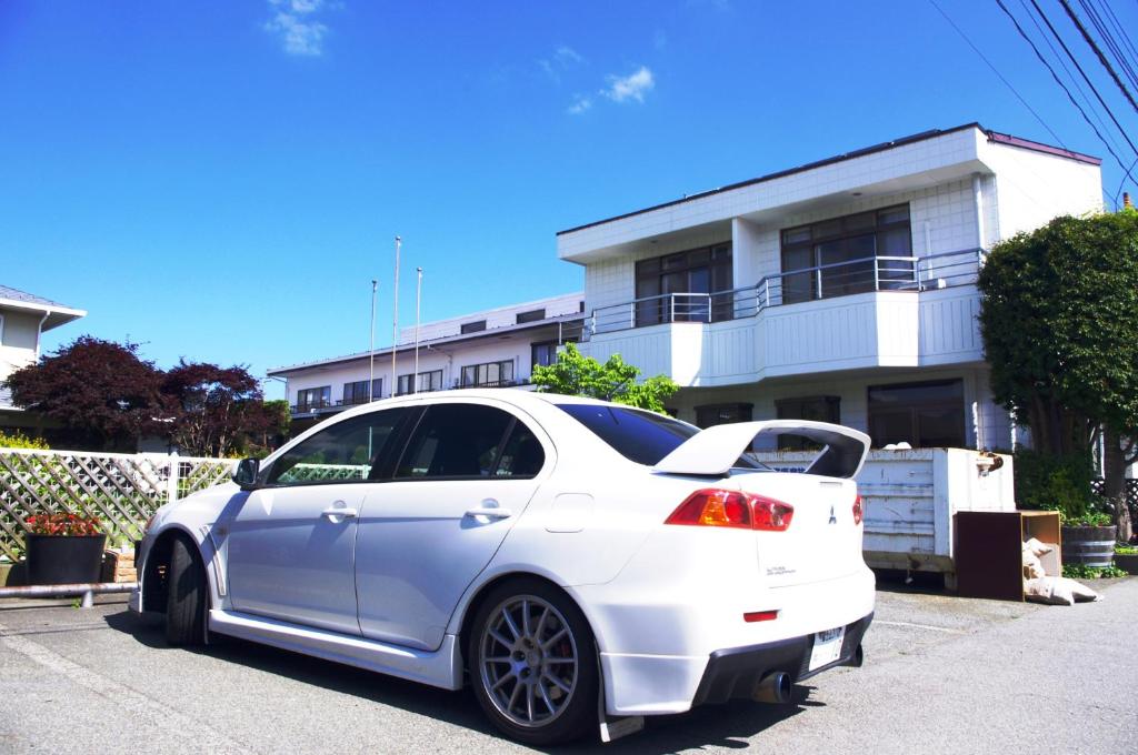 a white car parked in front of a house at K's House Fuji View - Travelers Hostel in Fujikawaguchiko