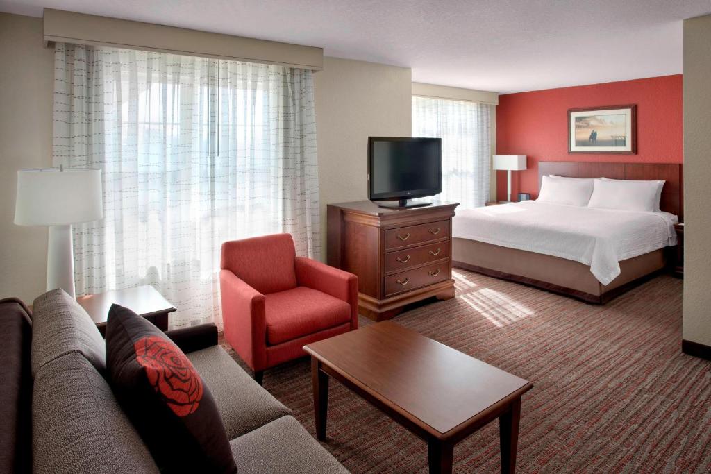 ein Hotelzimmer mit einem Bett, einem Sofa und einem TV in der Unterkunft Residence Inn by Marriott Saratoga Springs in Saratoga Springs