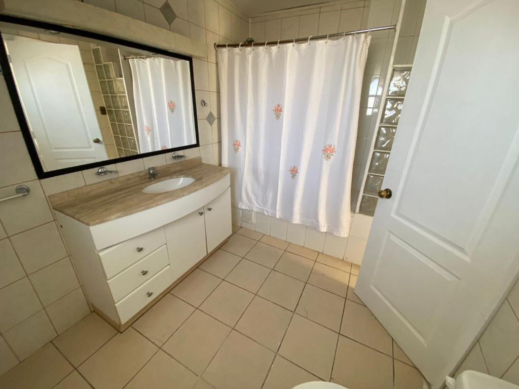 a white bathroom with a sink and a mirror at Casa en sector residencial in Arauco