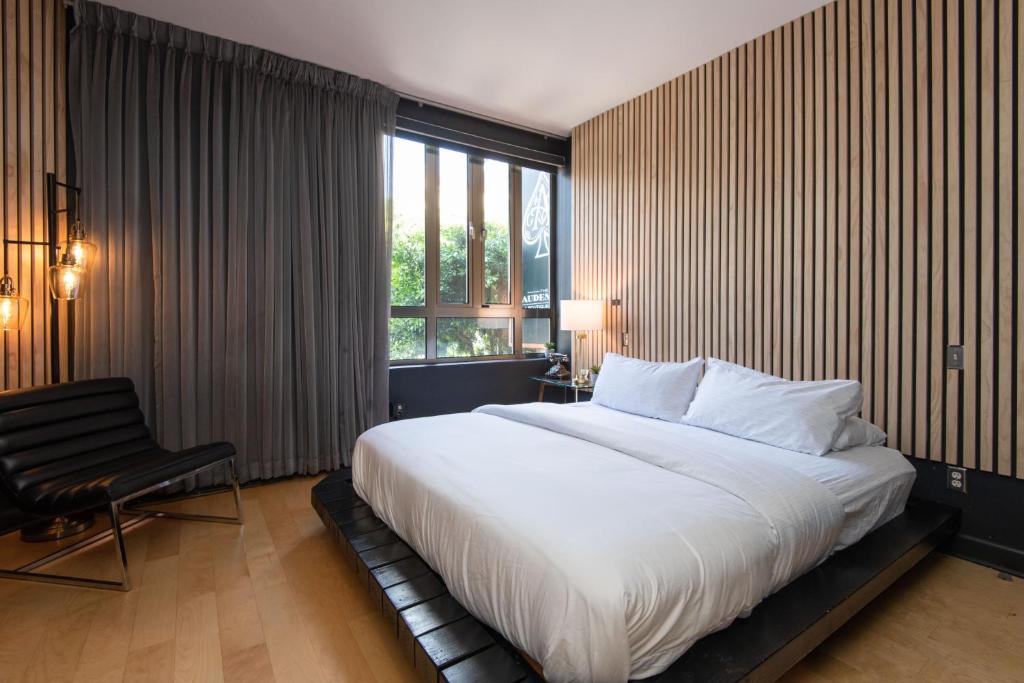 - une chambre avec un grand lit blanc et une chaise dans l'établissement Audemar Boutique Hotel and Apartment Homes, à Los Angeles