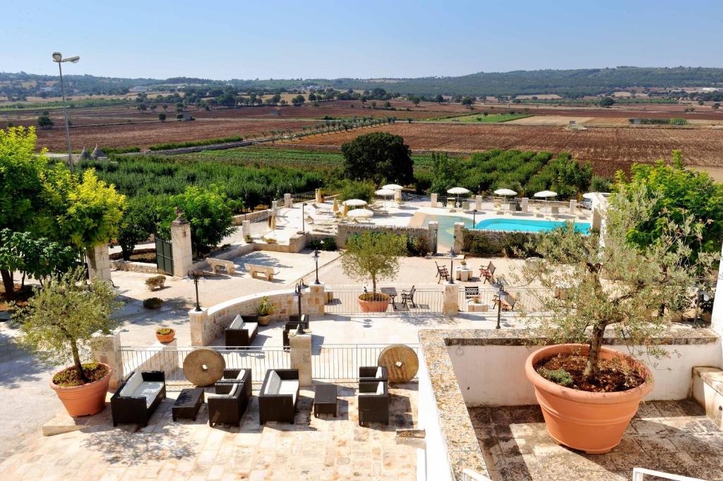 een resort met een zwembad, tafels, stoelen en bomen bij Masseria Torricella in Alberobello