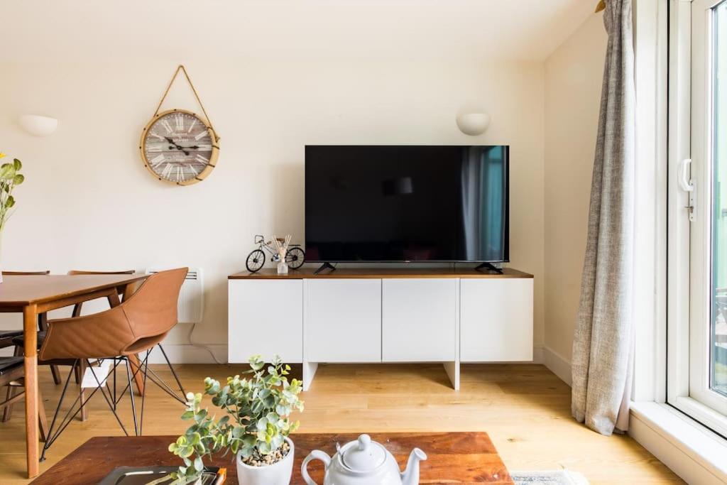 a living room with a tv on a white cabinet at Wild Roses Serviced Apartments - Tower Bridge in London