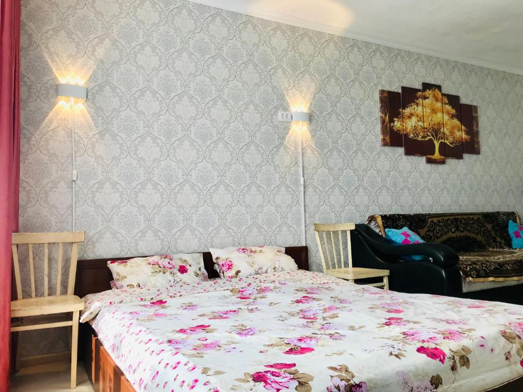 a bedroom with a bed with pink flowers on it at Flat in the city center in Karagandy