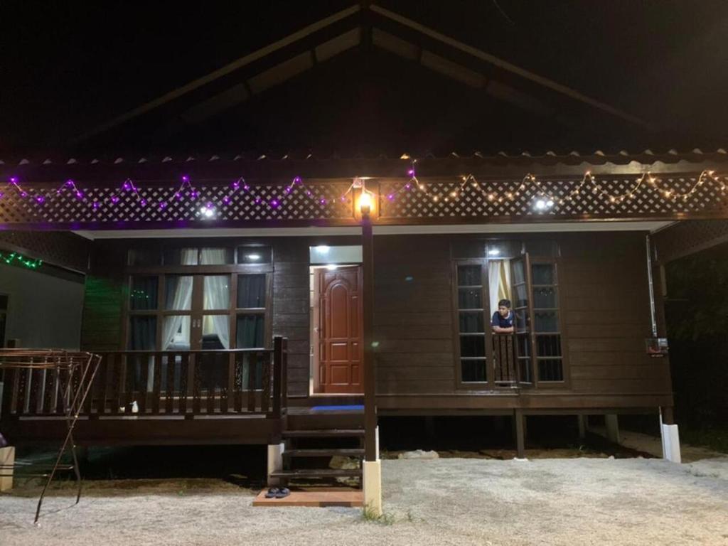 a house with a woman standing on the porch at night at Teratak Bayu STC in Kuala Terengganu