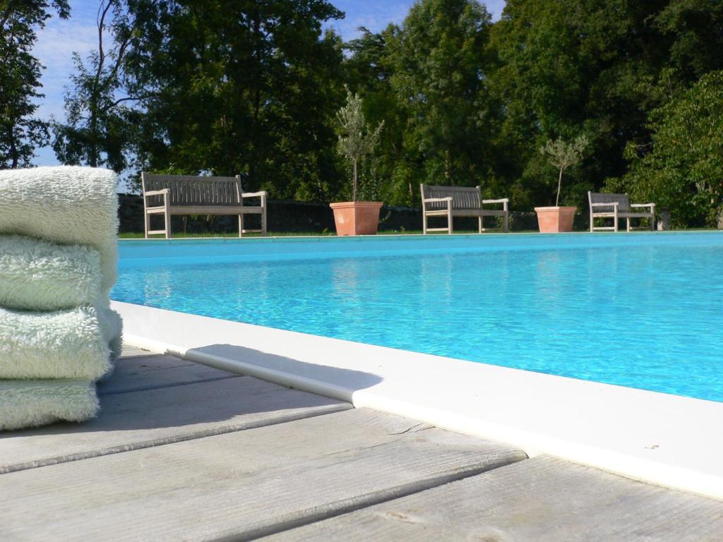 a swimming pool with chairs next to a swimming pool at Château de la Marronnière in Aizenay