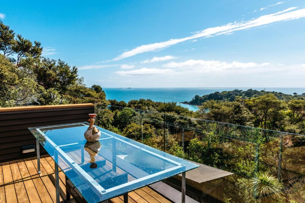 a man standing on top of a glass table on a balcony at Hekerua Heights - Stay Waiheke in Oneroa