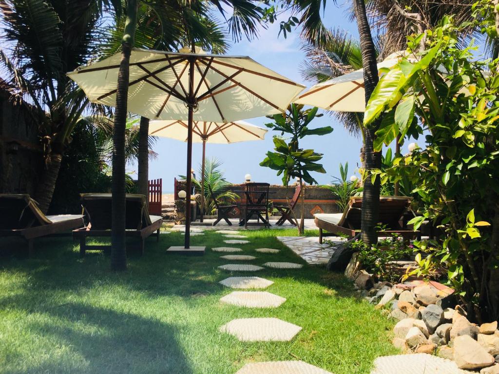a patio with an umbrella and chairs and tables at Sầm Sơn Boutique Hotel Phan Thiết in Phan Thiet