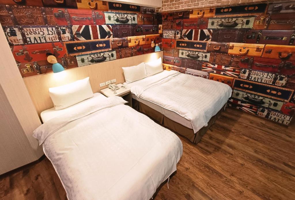 two beds in a room with a wall with posters at Sanduo Hotel in Kaohsiung