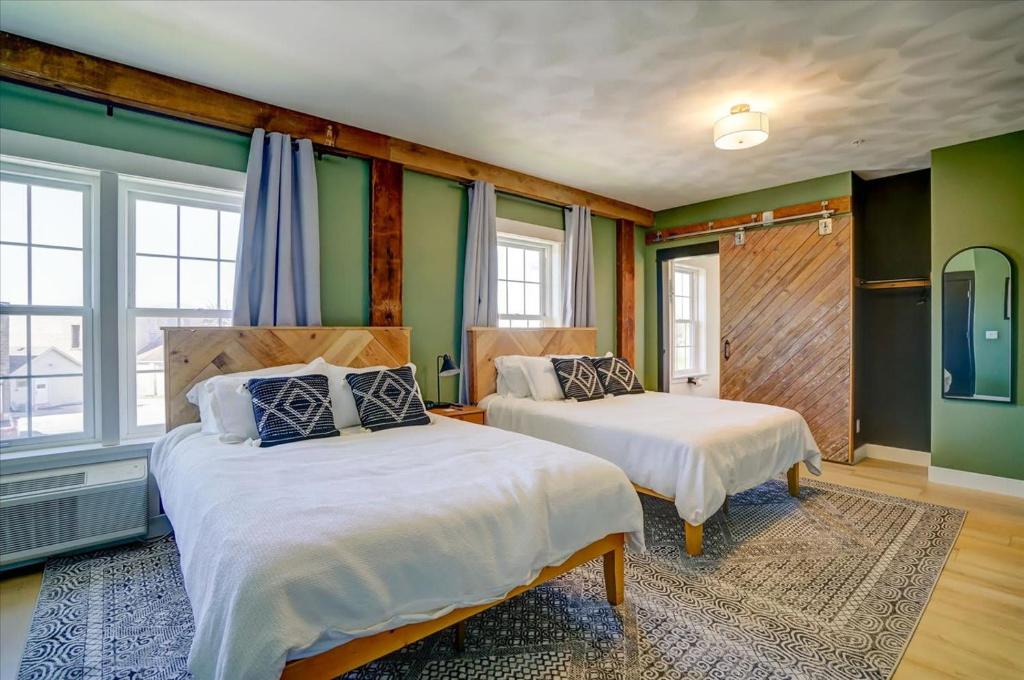 two beds in a room with green walls and windows at 203 - Double Queen in Waunakee
