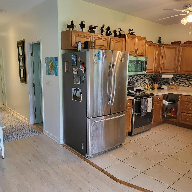 a kitchen with a stainless steel refrigerator and wooden cabinets at Hoomaikai Blessings in Keaau