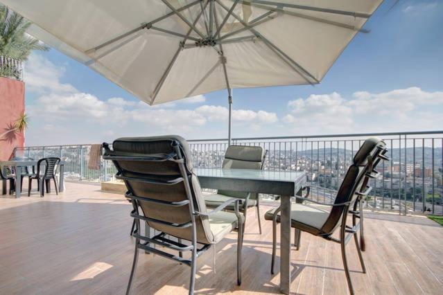 a table and chairs on a balcony with an umbrella at Holyland Apartments in Jerusalem