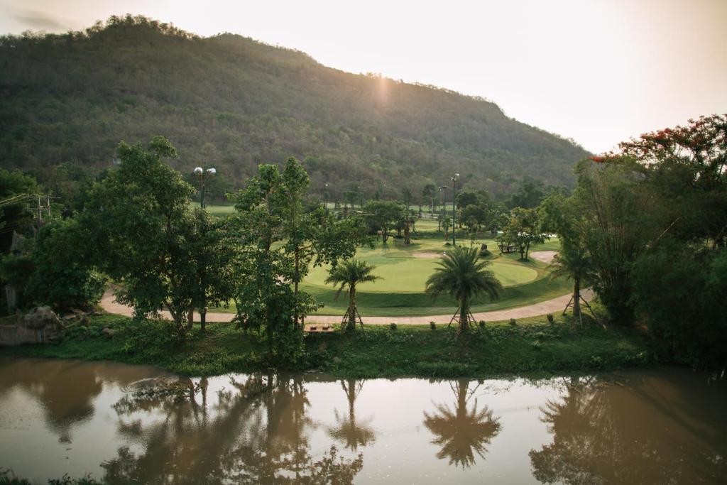 Phubachiang Golf and Resort Pakse في باكسي: ملعب قولف اشجار وجبل في الخلف