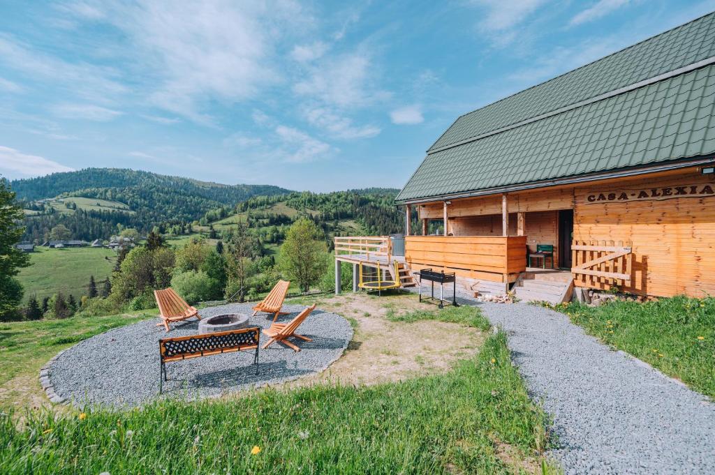 a cabin with chairs and a fire pit in front of it at Casa Alexia in Mătişeşti