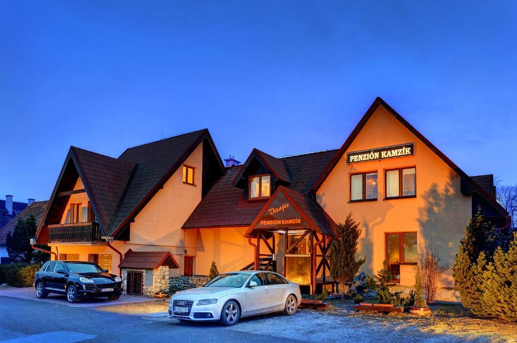 a house with two cars parked in front of it at Penzión Kamzik in Stará Lesná