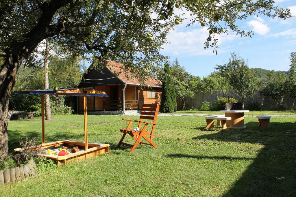 einen Stuhl, der in einem Garten neben einem Baum sitzt in der Unterkunft Szilvásvárad Camping & Apartman in Szilvásvárad