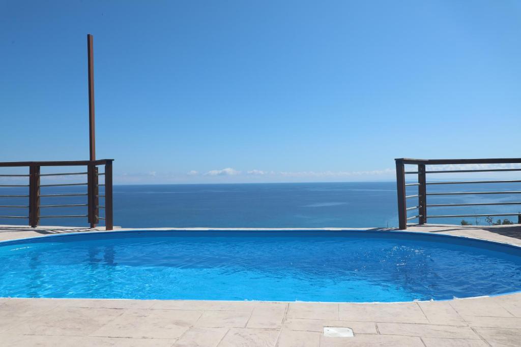 a large blue swimming pool next to the water at Zante Xigia Bay villas in Khartáta