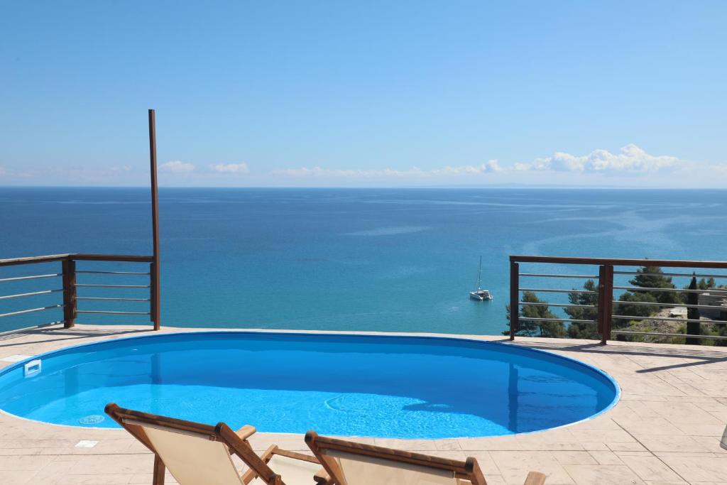 a swimming pool with two chairs and a view of the water at Zante Xigia Bay villas in Khartáta
