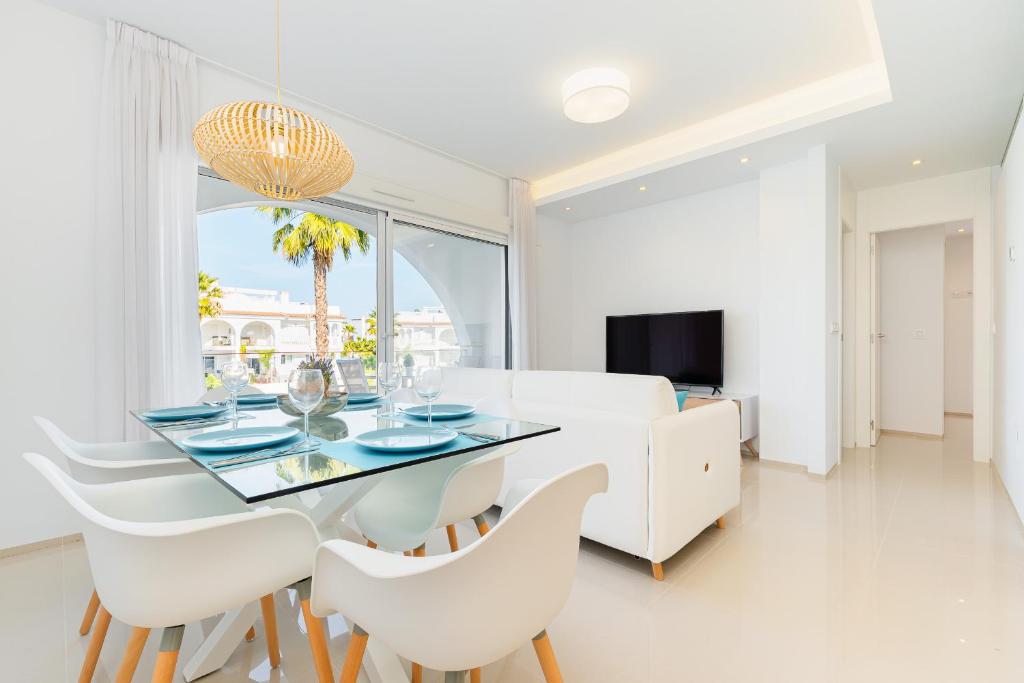 une salle à manger avec une table en verre et des chaises blanches dans l'établissement Apartamento Natural Luxury Park, à Ciudad Quesada