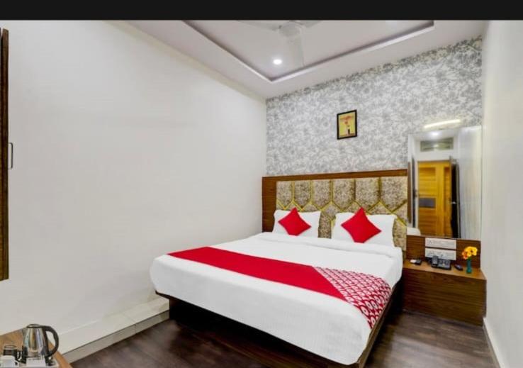a bedroom with a large bed with red pillows at HOTEL SAROVAR INN in Ahmedabad