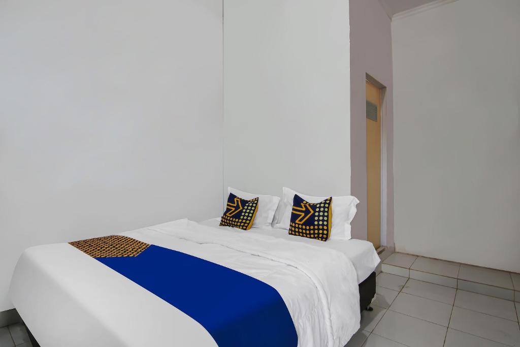 Bett mit blauer und weißer Bettwäsche und Kissen in der Unterkunft SPOT ON 92498 Fanni Homestay in Pekanbaru
