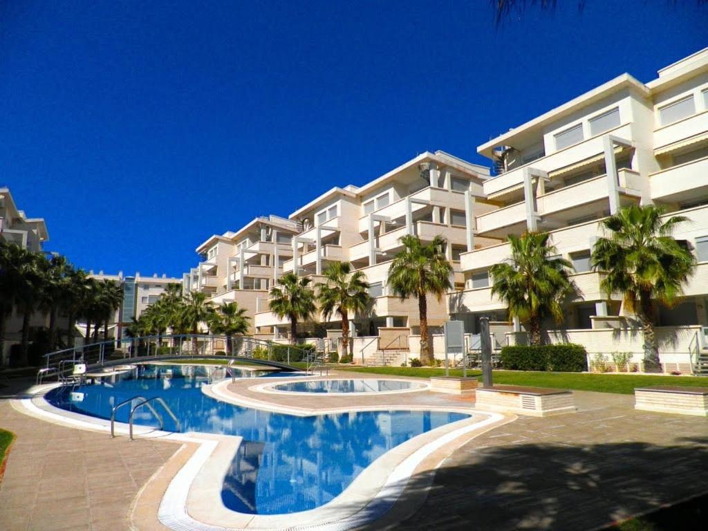 un gran edificio de apartamentos con piscina y palmeras en Residencial Elegance, en Denia