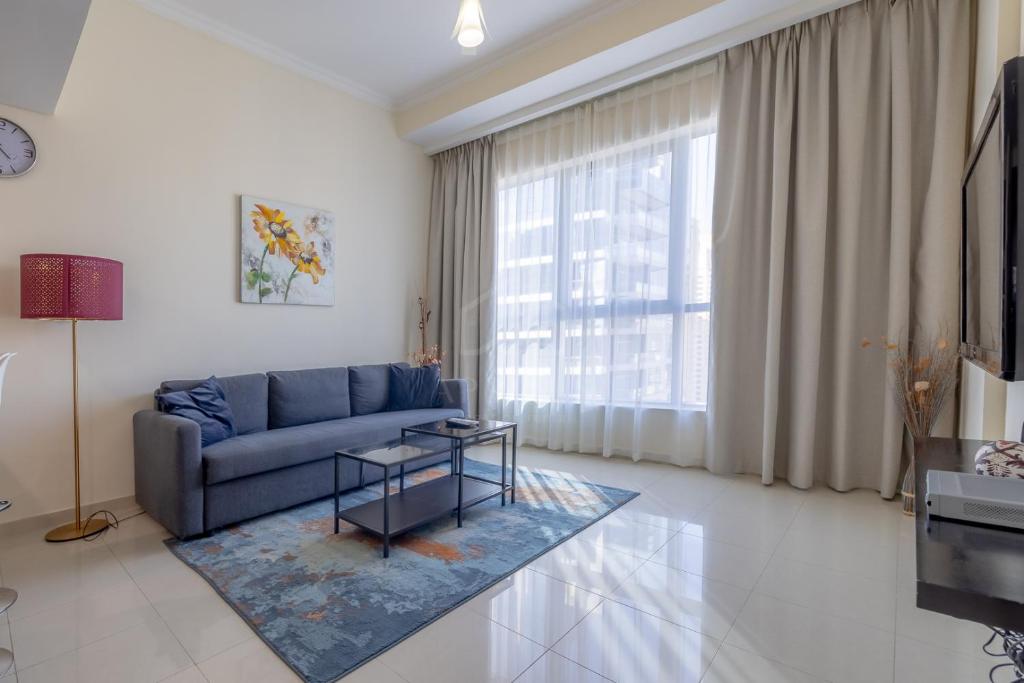 a living room with a blue couch and a large window at Awesome Marina Canal View 1BD Bay Central Marina in Dubai