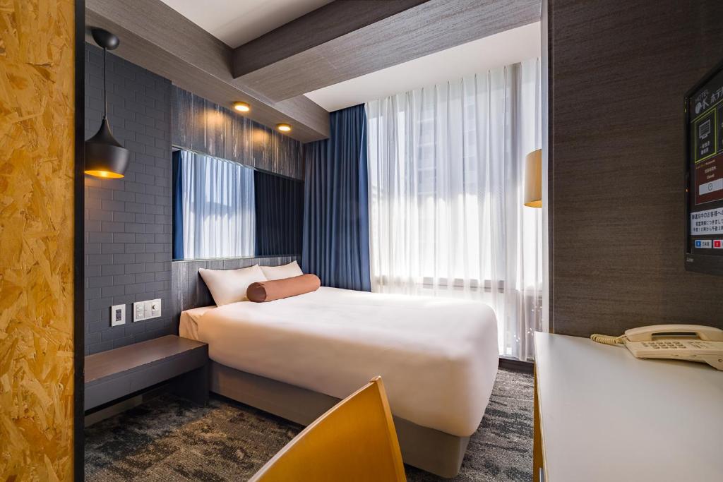 静岡市にあるホテル オーク 静岡のベッドとデスクが備わるホテルルームです。