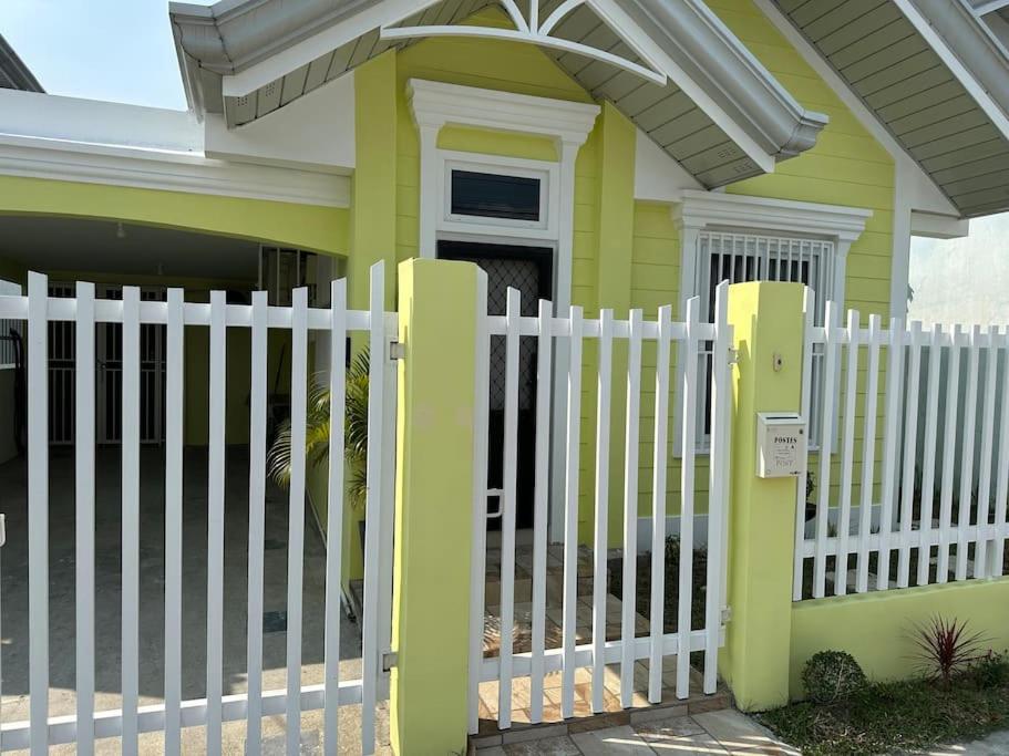 una cerca blanca frente a una casa amarilla en 4 Bedroom Bungalow, Angeles City en Ángeles