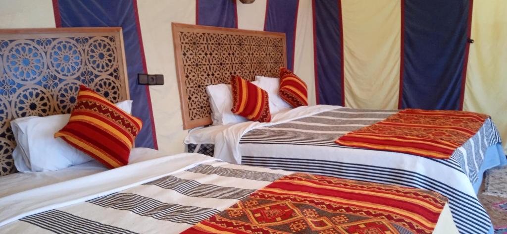 two beds sitting next to each other in a room at Désert Man luxury Camp in Merzouga