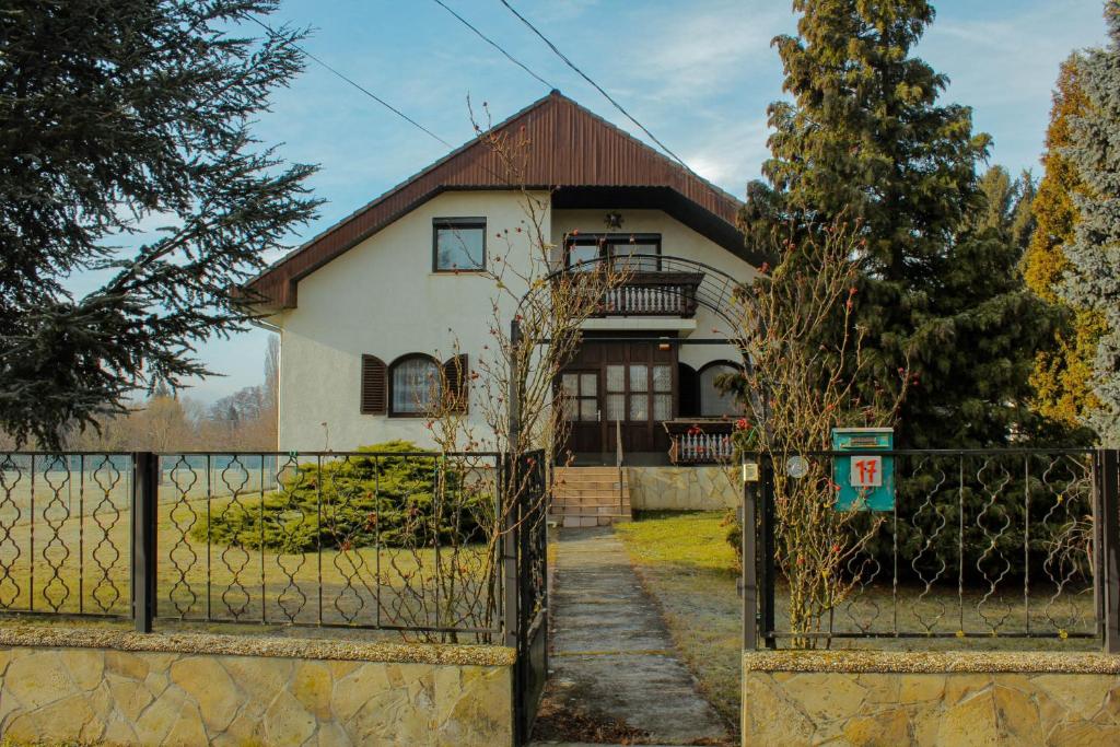 una casa blanca con una valla y una puerta en ZOLI'BÁ Apartman, en Gyöngyösfalu