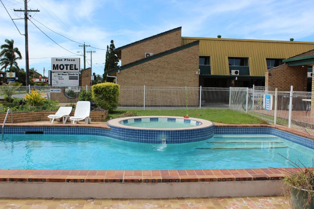 a swimming pool with two chairs and a building at Sun Plaza Motel - Mackay in Mackay